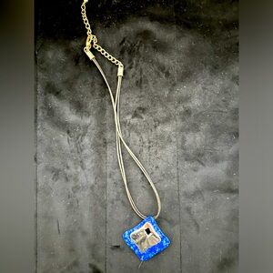 Blue metal pendant on dark leather necklace